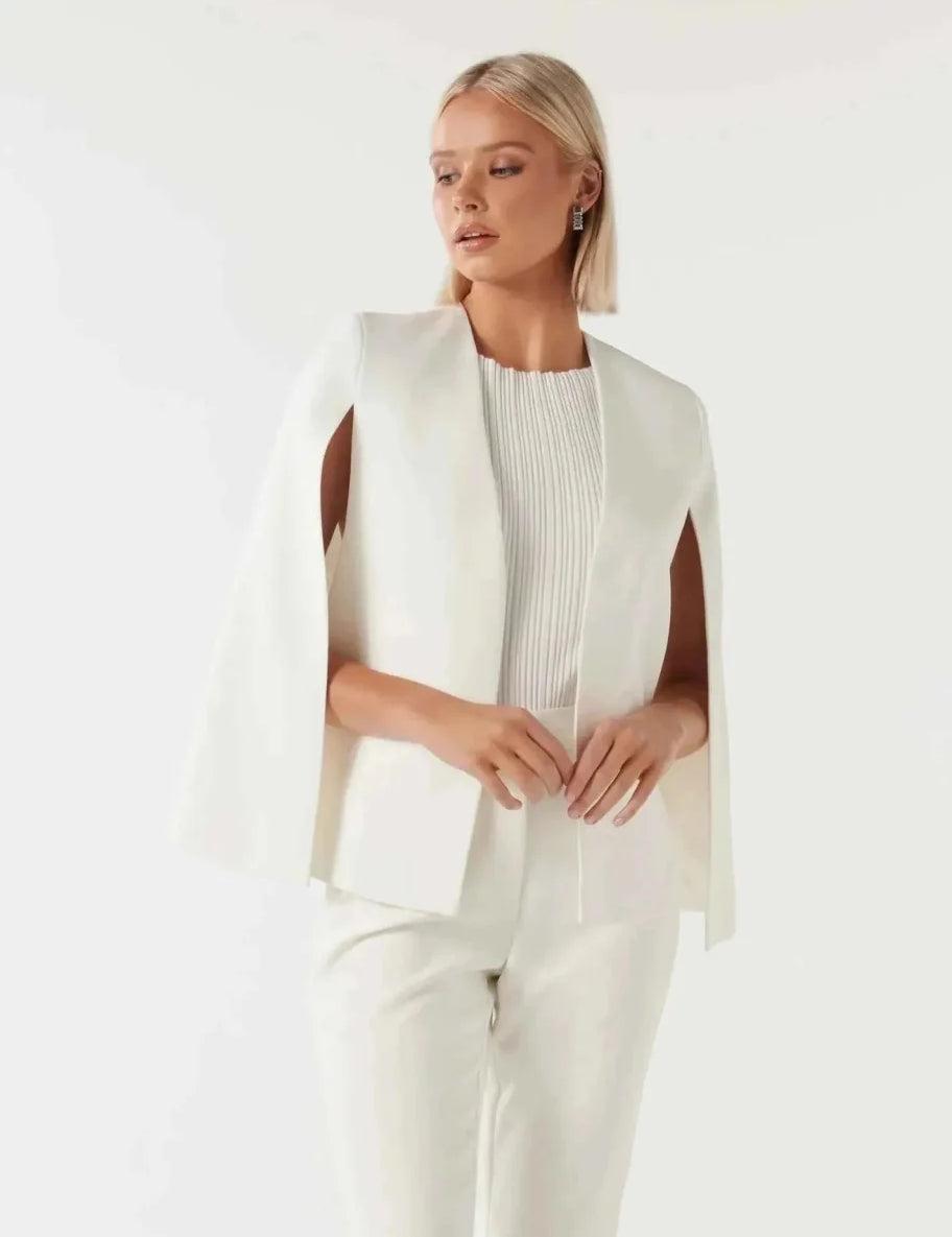 Blazer cape da donna con maniche a spacco su sfondo neutro