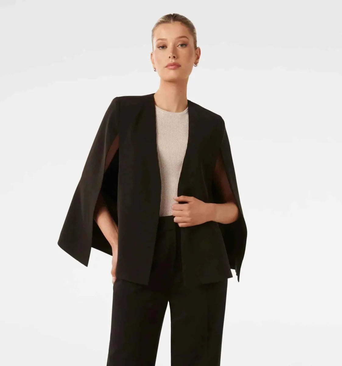 Donna indossa blazer cape bianco con pantaloni sartoriali